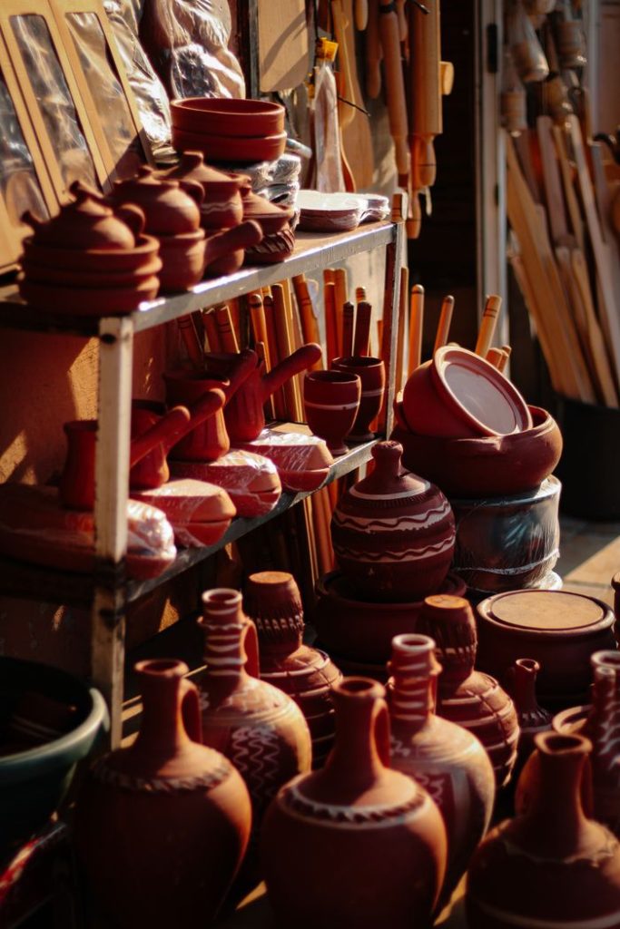 Variety of handcrafted pottery on display at an open-air market, warm earthy tones.